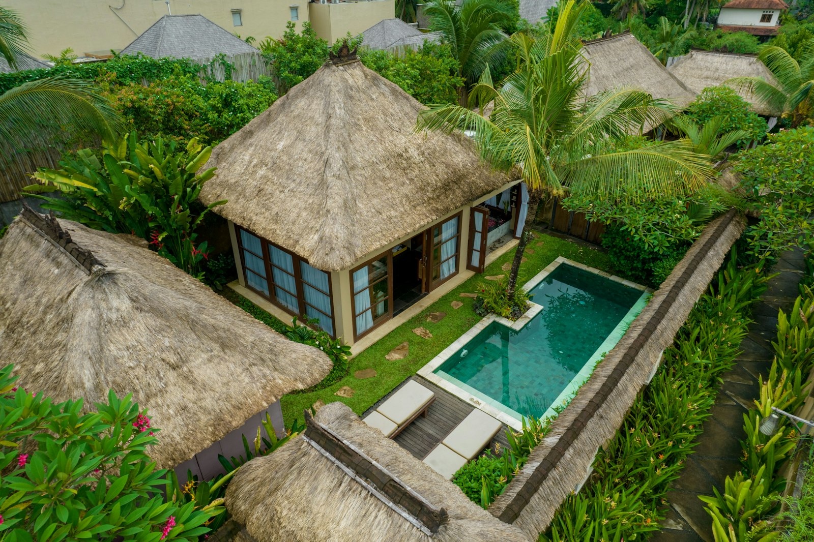 Bungalow beratap ilalang dengan kolam kecil dilihat dari atas